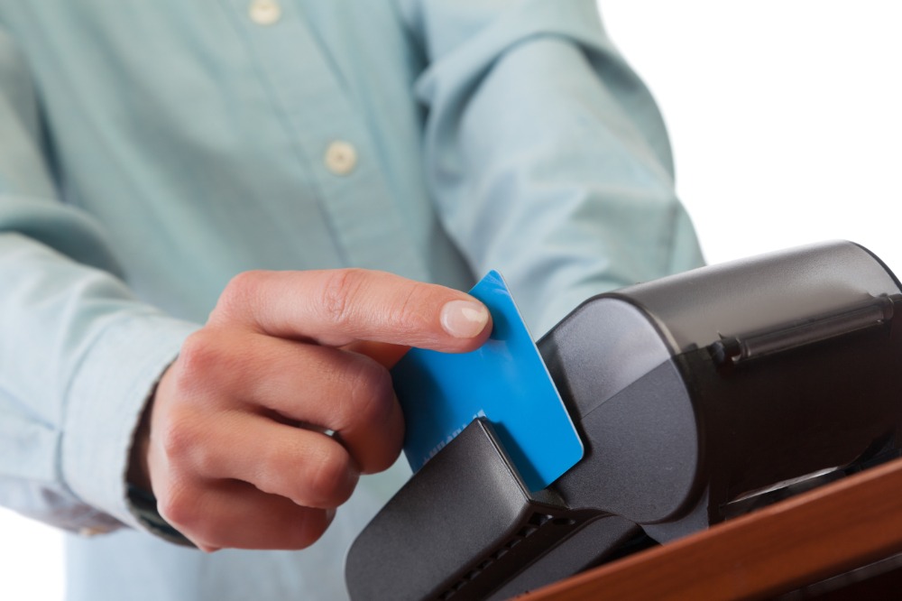Human hand with credit card swipe through terminal for sale. orthodontist littleton co